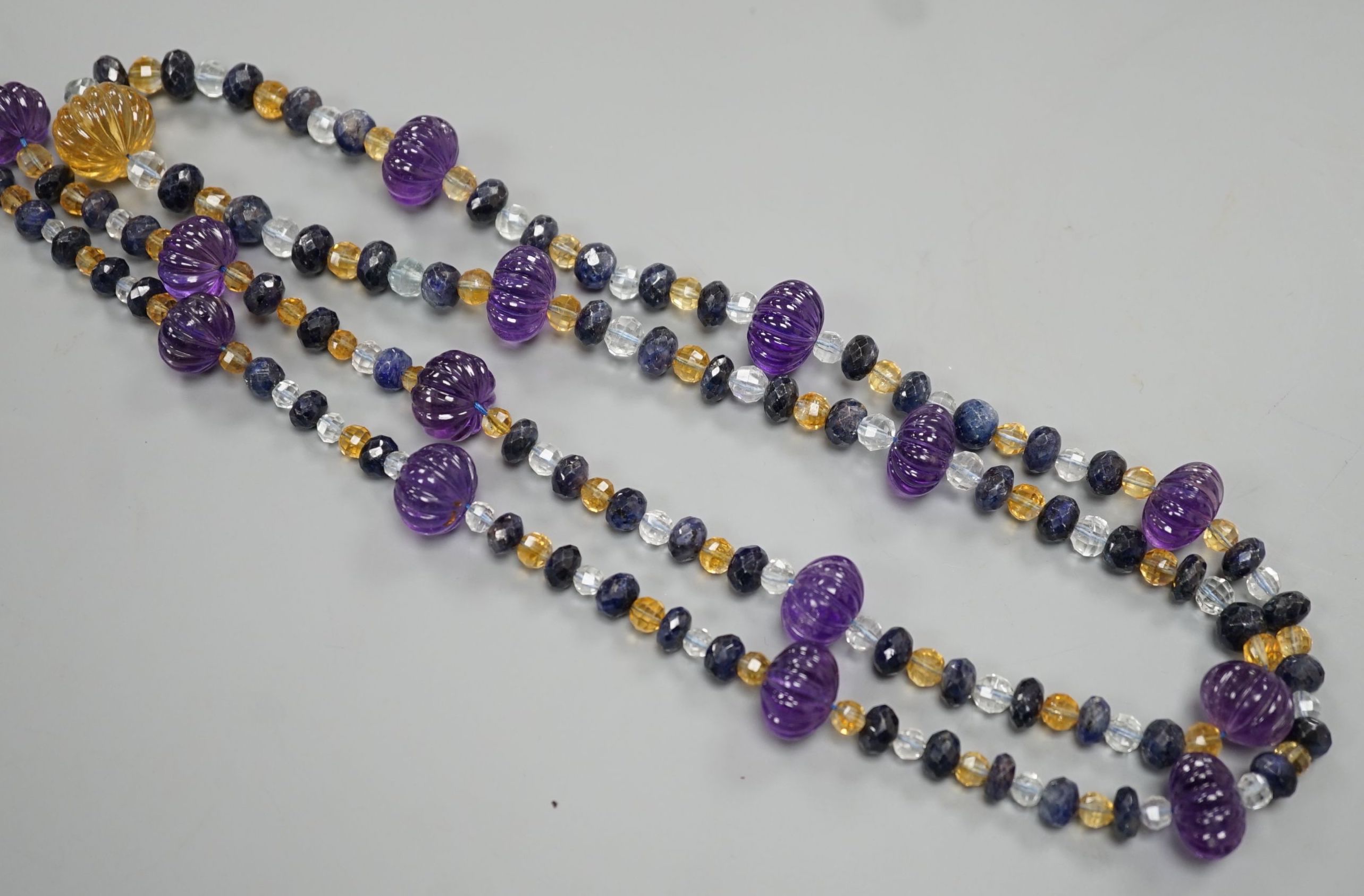 A modern single strand fluted amethyst and facet cut sapphire, citrine and aquamarine bead set necklace, 134cm.